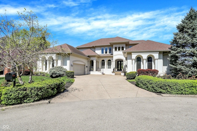 mediterranean / spanish-style home featuring an attached garage, roof with shingles, stucco siding, and concrete driveway
