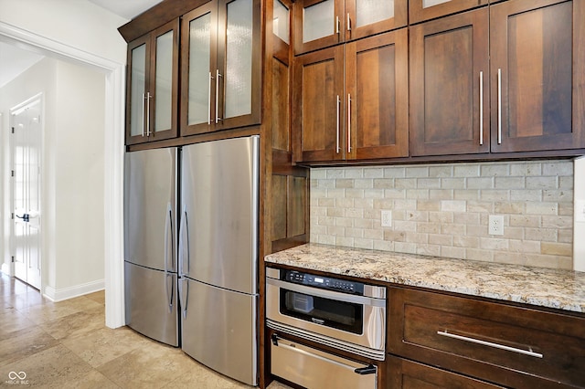 kitchen with tasteful backsplash, stainless steel refrigerator, baseboards, a warming drawer, and oven