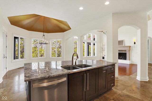 kitchen with dishwasher, a sink, baseboards, light stone counters, and open floor plan