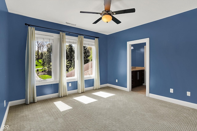 carpeted spare room with ceiling fan, visible vents, and baseboards