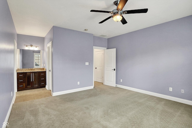 unfurnished bedroom featuring a ceiling fan, baseboards, light carpet, and ensuite bath