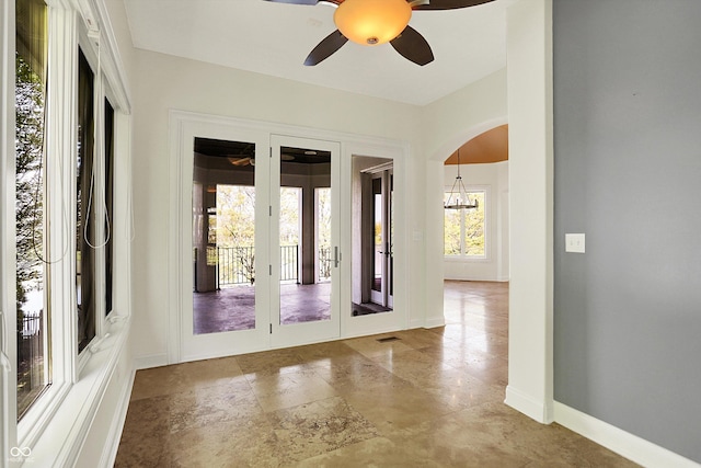interior space featuring baseboards, arched walkways, ceiling fan, and french doors