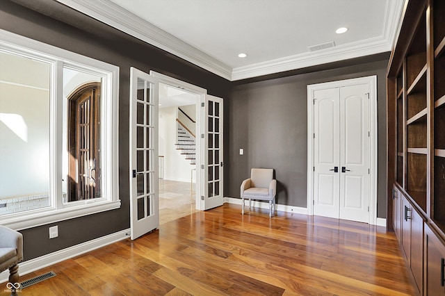 living area featuring french doors, visible vents, wood finished floors, ornamental molding, and stairs