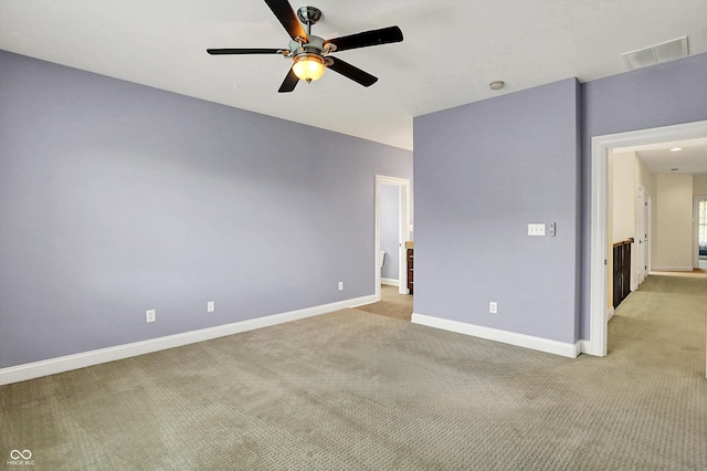 unfurnished room with ceiling fan, light colored carpet, baseboards, and visible vents