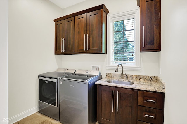 washroom featuring independent washer and dryer, cabinet space, a sink, baseboards, and light tile patterned floors