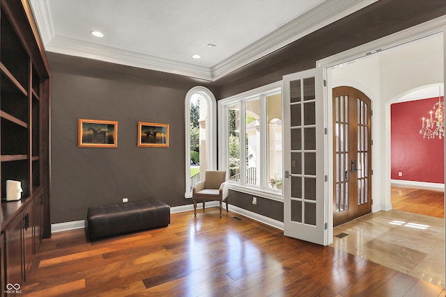 sitting room with french doors, hardwood / wood-style flooring, baseboards, a chandelier, and ornamental molding