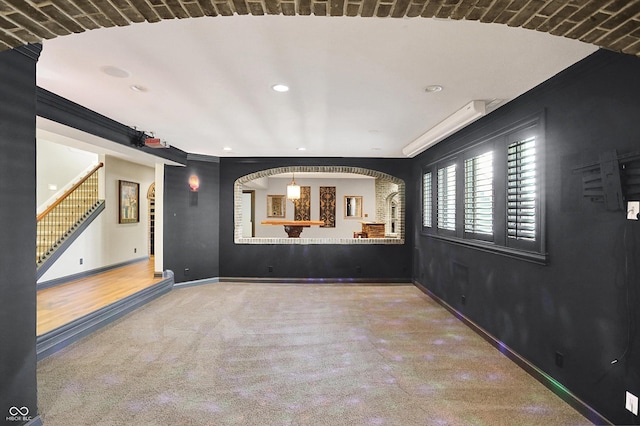 spare room with arched walkways, stairs, baseboards, carpet flooring, and recessed lighting