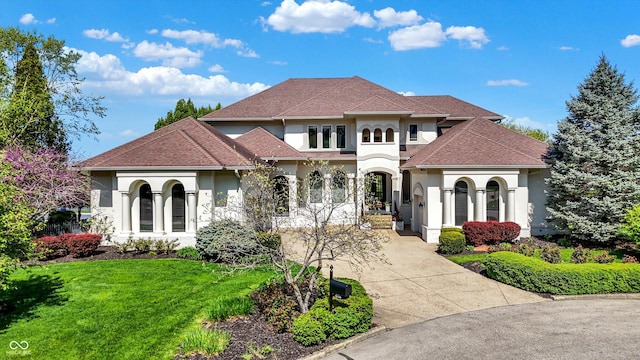 mediterranean / spanish-style home featuring a front lawn, roof with shingles, stucco siding, and driveway