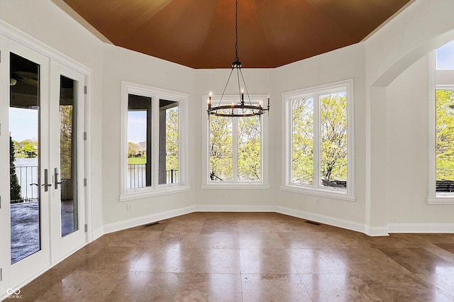 unfurnished dining area featuring french doors, visible vents, arched walkways, baseboards, and a chandelier