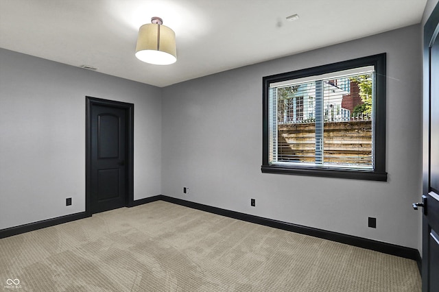 spare room with baseboards, visible vents, and light carpet