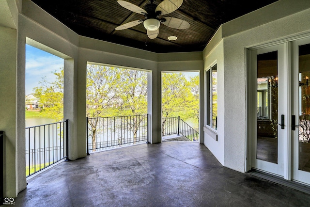 unfurnished sunroom with a water view and ceiling fan