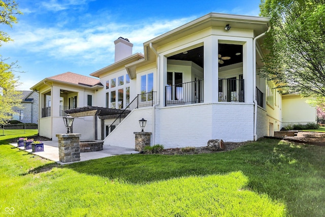 back of property featuring a chimney, a yard, stairway, and brick siding
