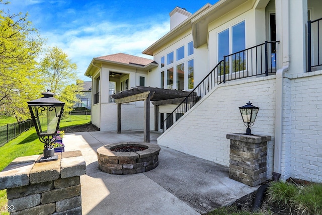 view of patio / terrace featuring fence, stairs, and an outdoor fire pit