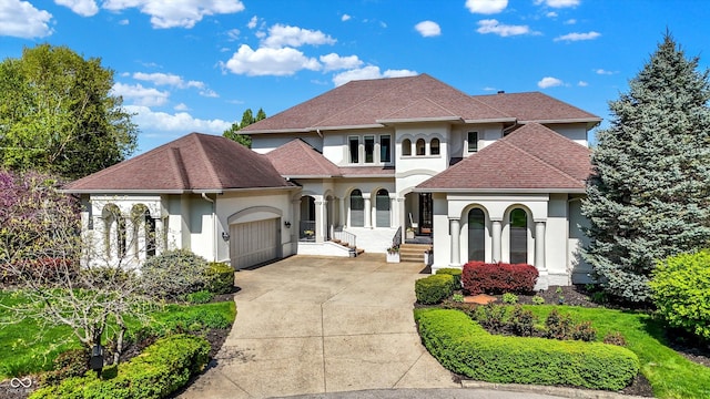 mediterranean / spanish home with an attached garage, roof with shingles, stucco siding, and concrete driveway