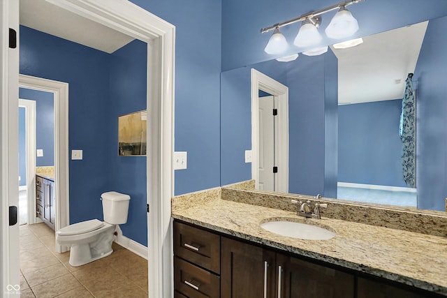 bathroom with toilet, baseboards, tile patterned flooring, and vanity