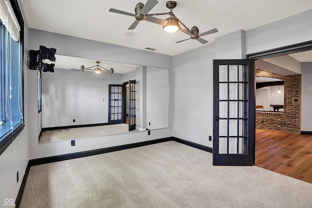 carpeted empty room with baseboards, a ceiling fan, and visible vents