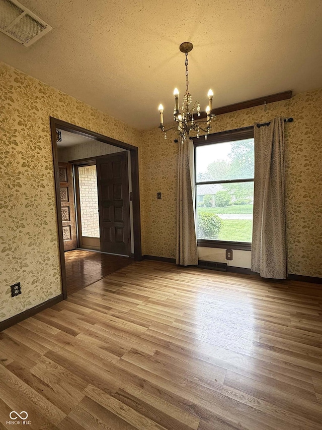 645 Boulder Rd, Indianapolis, IN 46217 - unfurnished dining area featuring visible vents, wallpapered walls, wood finished floors, and an inviting chandelier