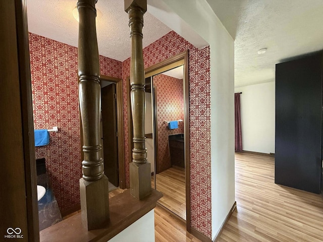 645 Boulder Rd, Indianapolis, IN 46217 - hallway featuring baseboards, light wood-style flooring, wallpapered walls, and a textured ceiling