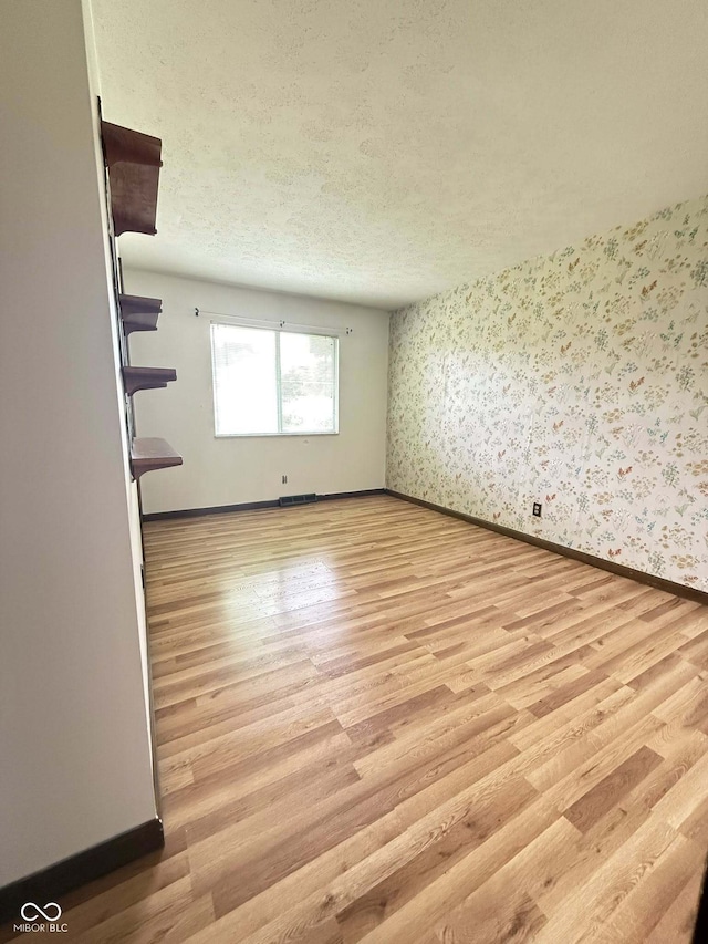 645 Boulder Rd, Indianapolis, IN 46217 - spare room featuring a textured ceiling, light wood finished floors, and wallpapered walls