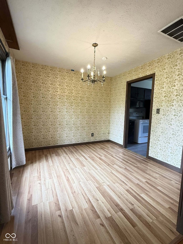 645 Boulder Rd, Indianapolis, IN 46217 - unfurnished dining area featuring an inviting chandelier, a textured ceiling, wallpapered walls, wood finished floors, and visible vents