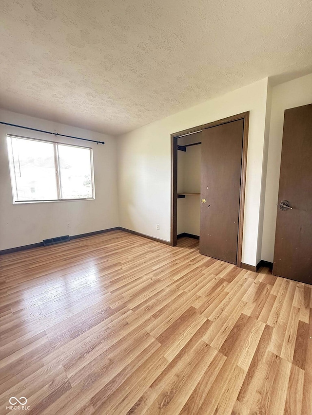 645 Boulder Rd, Indianapolis, IN 46217 - unfurnished bedroom featuring light wood-style floors, baseboards, a closet, and a textured ceiling