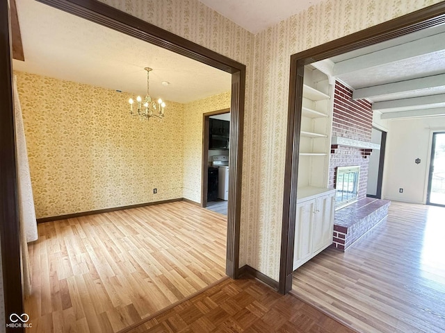 645 Boulder Rd, Indianapolis, IN 46217 - unfurnished dining area with a brick fireplace, wood finished floors, baseboards, a chandelier, and wallpapered walls