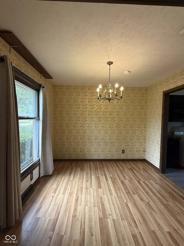 645 Boulder Rd, Indianapolis, IN 46217 - unfurnished dining area featuring a textured ceiling, wallpapered walls, a chandelier, and light wood finished floors