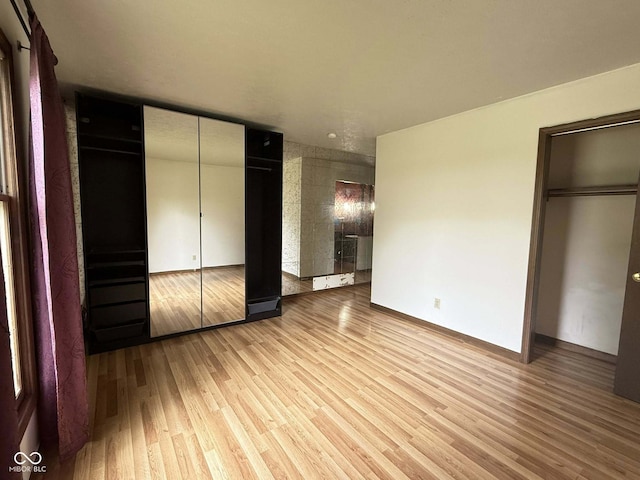 645 Boulder Rd, Indianapolis, IN 46217 - unfurnished bedroom with baseboards, light wood finished floors, and two closets