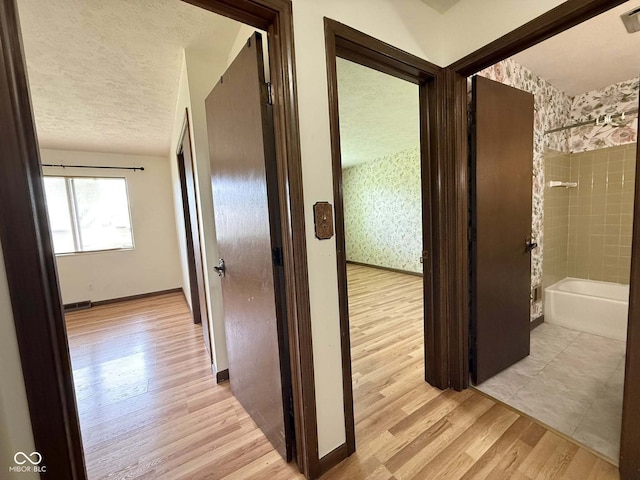 645 Boulder Rd, Indianapolis, IN 46217 - hall with light wood-style floors, baseboards, wallpapered walls, and a textured ceiling