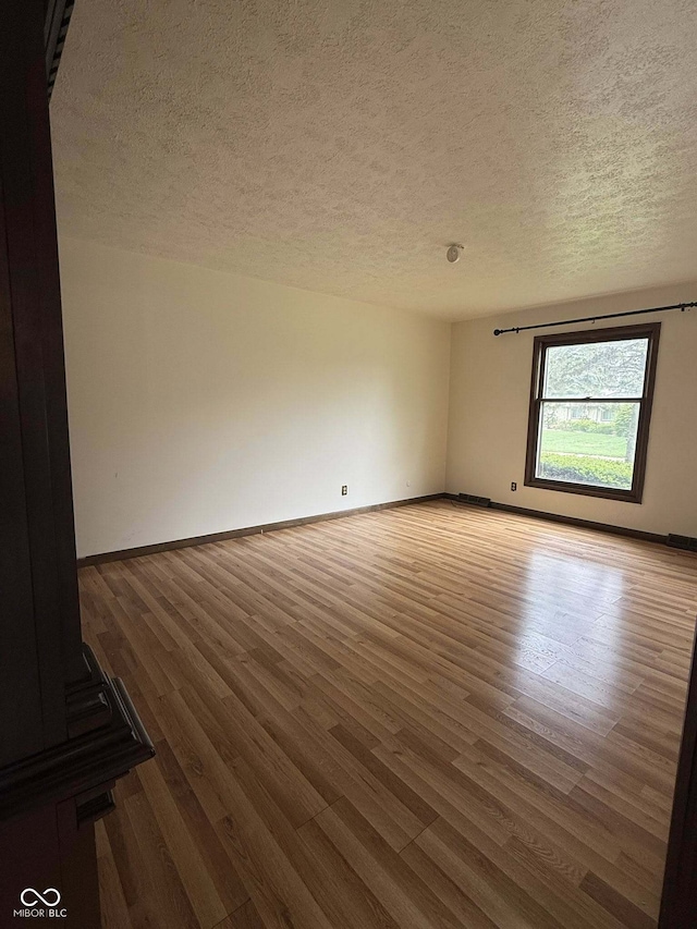 645 Boulder Rd, Indianapolis, IN 46217 - unfurnished room with baseboards, a textured ceiling, and wood finished floors