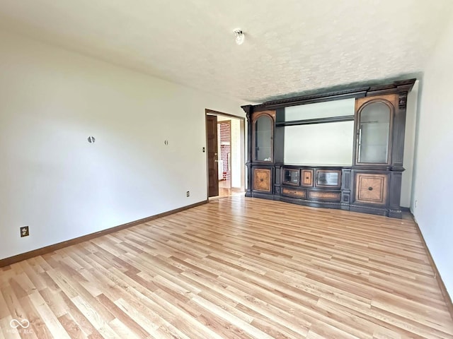 645 Boulder Rd, Indianapolis, IN 46217 - unfurnished living room with baseboards, light wood finished floors, and a textured ceiling