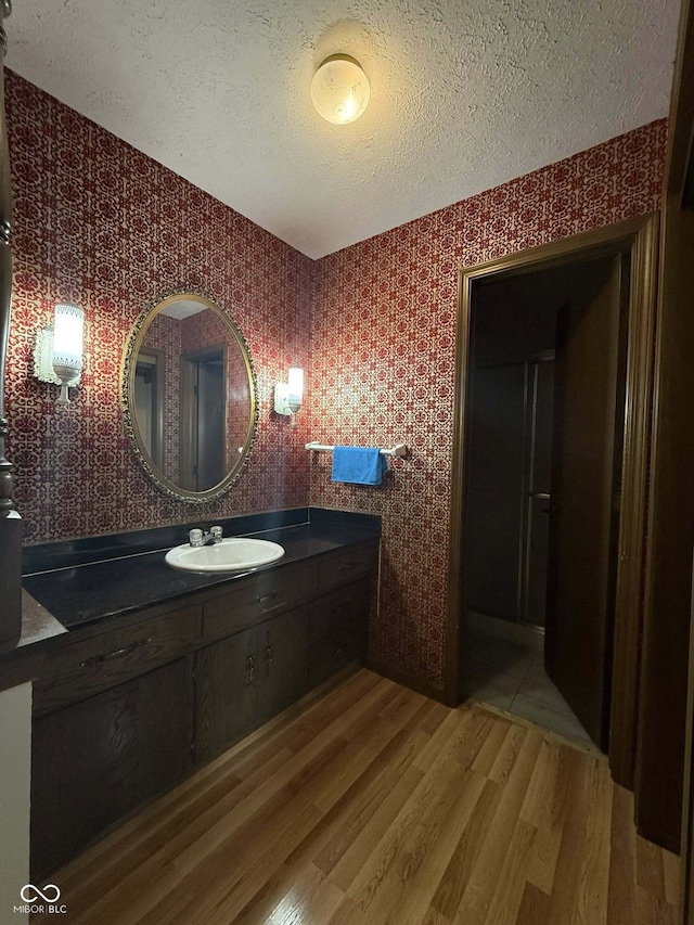 645 Boulder Rd, Indianapolis, IN 46217 - bathroom with a textured ceiling, wallpapered walls, wood finished floors, and vanity