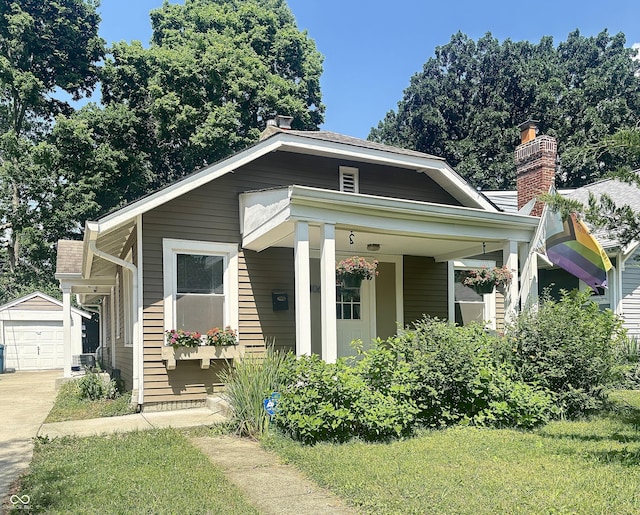 4406 Carrollton Ave, Indianapolis, IN 46205 - view of front of property with an outbuilding, driveway, a chimney, and covered porch