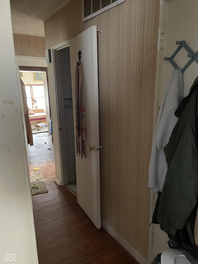 corridor with wood finished floors and wooden walls