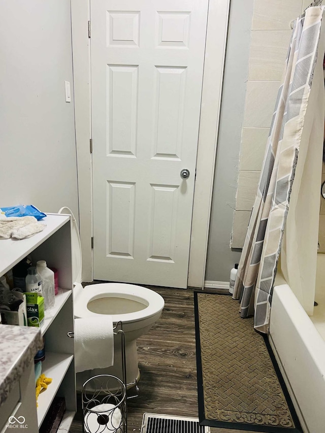 full bath with shower / bath combo with shower curtain, toilet, and wood finished floors