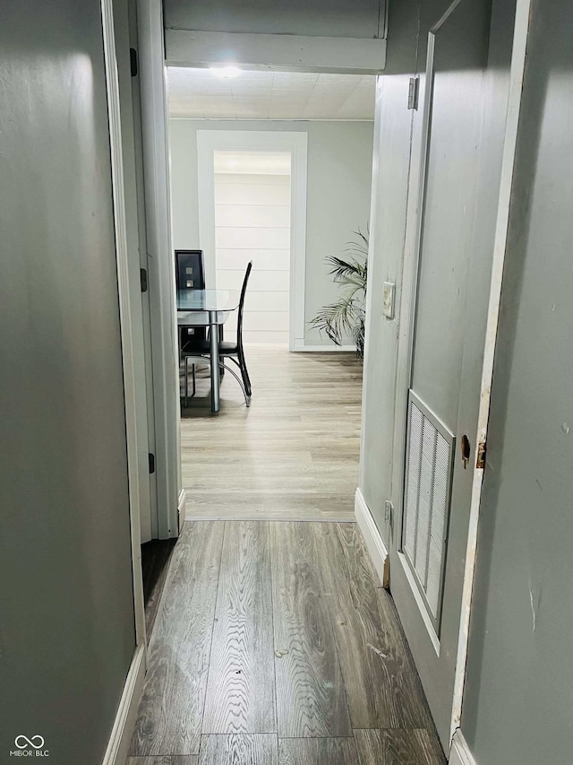 corridor with baseboards and wood finished floors