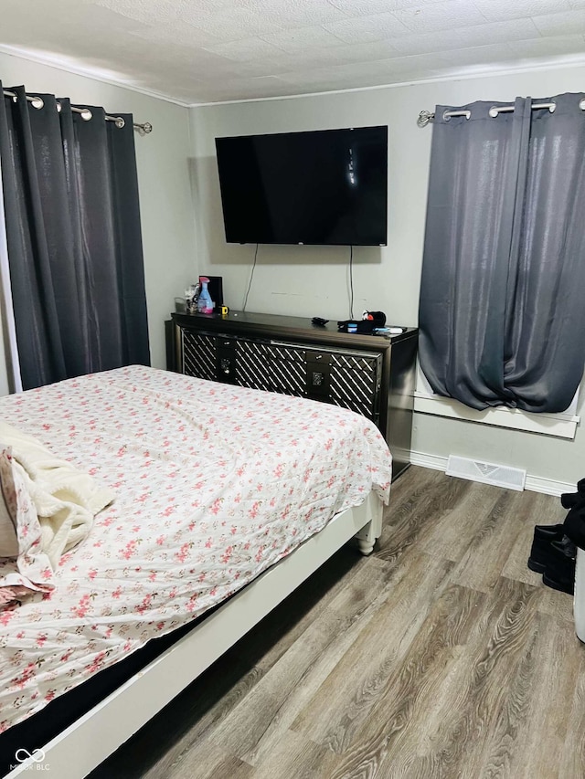 bedroom with baseboards, wood finished floors, and visible vents