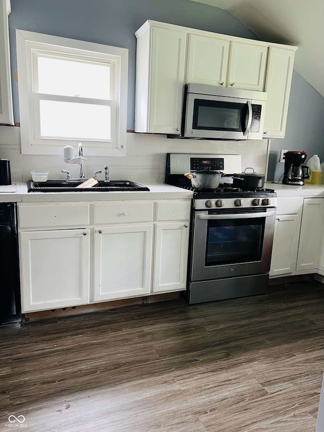 kitchen with vaulted ceiling, light countertops, stainless steel appliances, and a sink
