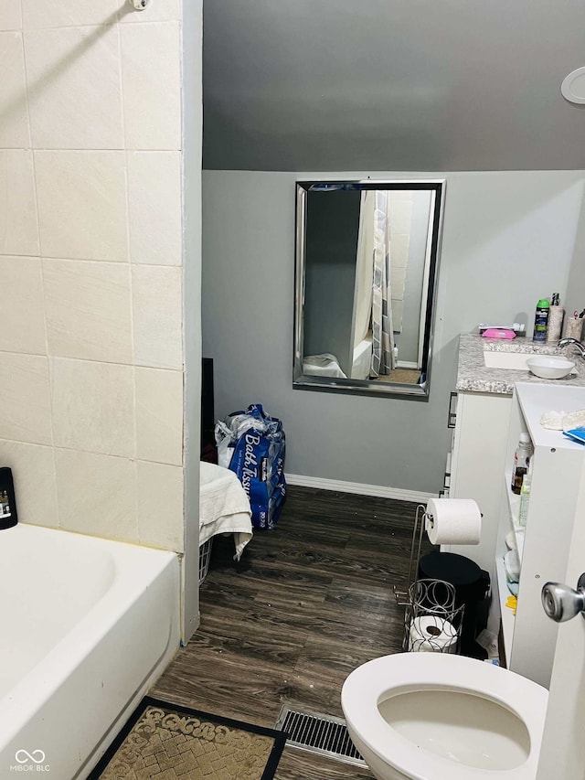 full bathroom with a sink, toilet, baseboards, wood finished floors, and visible vents