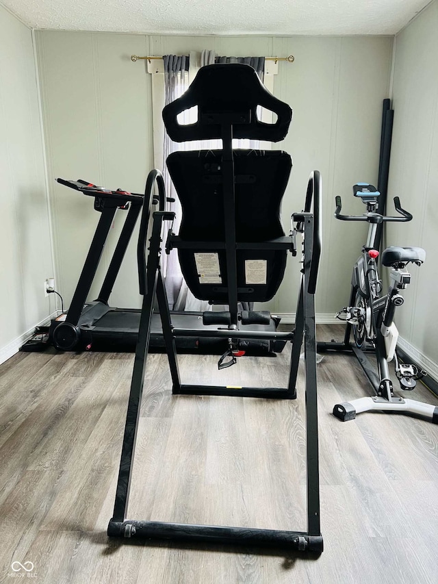 workout area with baseboards, a decorative wall, and wood finished floors