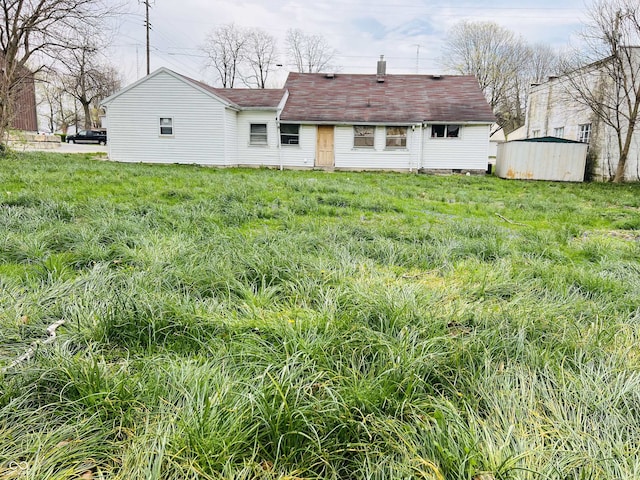back of house featuring a storage shed, an outbuilding, and a yard