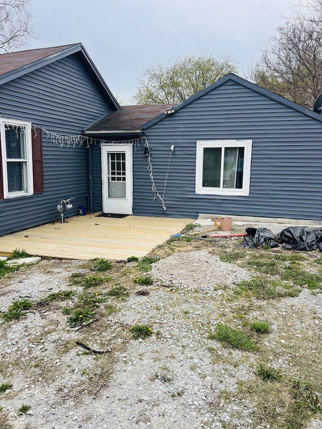 rear view of house featuring roof with shingles and a wooden deck