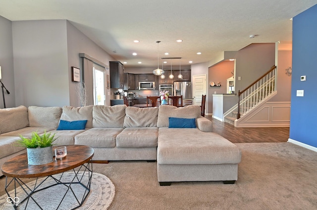 carpeted living area featuring stairs, wood finished floors, a wainscoted wall, baseboards, and recessed lighting