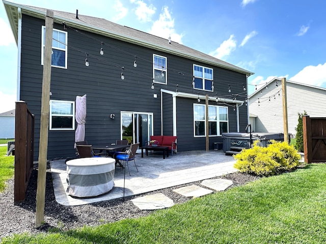 back of property featuring fence, a yard, a hot tub, and a patio area