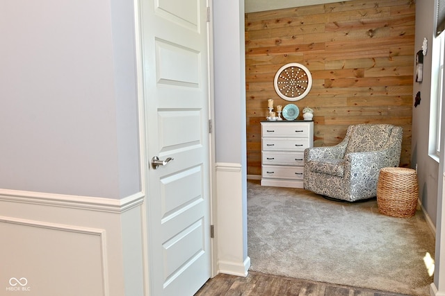 sitting room featuring carpet, wood walls, and wood finished floors