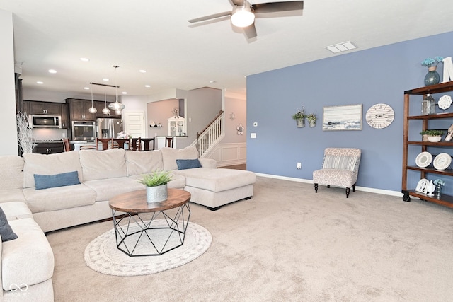 living area with light colored carpet, a ceiling fan, recessed lighting, visible vents, and stairway