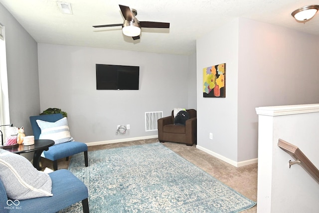 sitting room featuring visible vents, a ceiling fan, carpet, and an upstairs landing