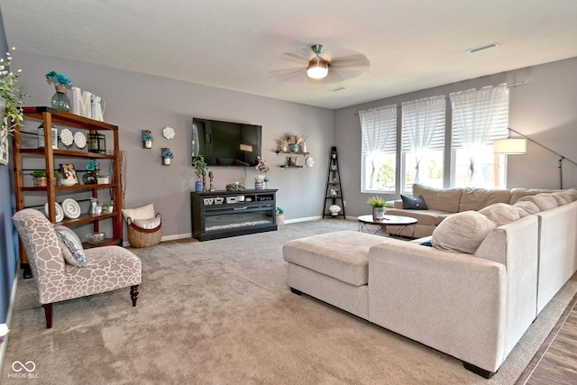 living room featuring visible vents, baseboards, ceiling fan, and carpet floors