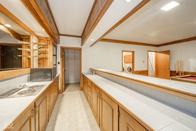 interior space featuring crown molding, tile countertops, washing machine and dryer, and a sink