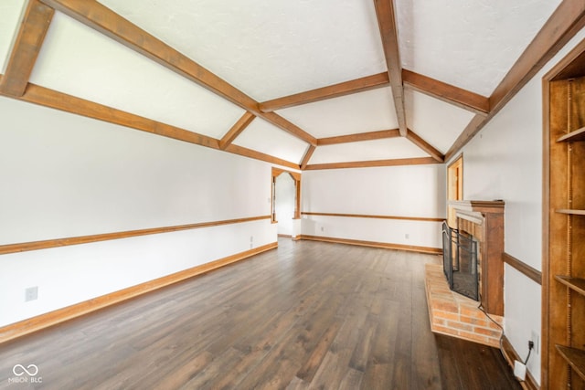 unfurnished living room featuring vaulted ceiling with beams, dark wood finished floors, a brick fireplace, and baseboards